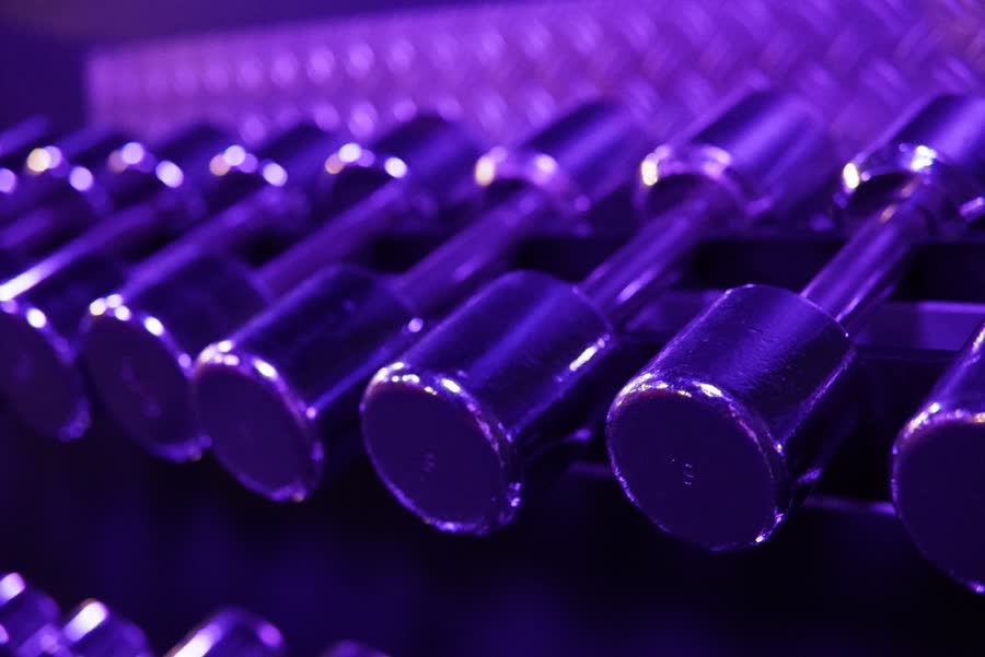Rangée d'haltères chromés éclairés en violet, vue rapprochée
