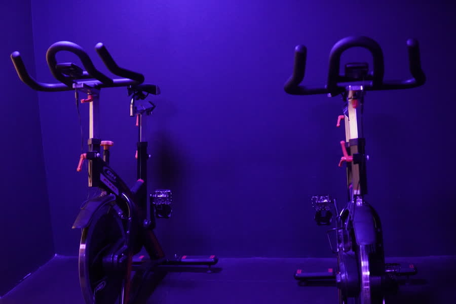 Deux vélos d'indoor cycling dans une pièce éclairée en violet